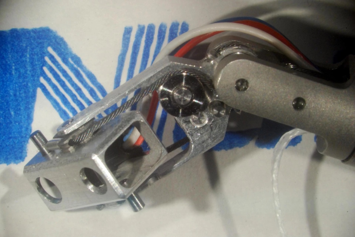 The miniature pan-tilt camera head in machined aluminium, driven by a thin tungsten cable over a pulley