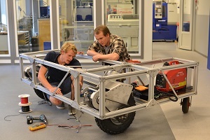 Two students building an aluminium-frame field robot in a lab